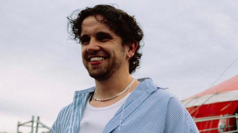 Matt Cominotto looking to the left of the camera, with a grey sky behind him