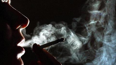 Woman smoking a rolled up cigarette or cannabis