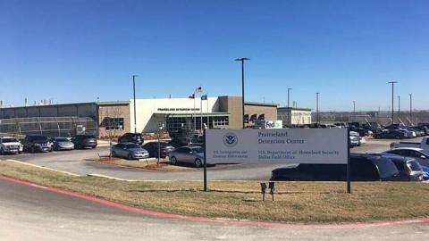 An exterior view of the Prairieland Detention Center in Alvarado, Texas, showing its signage and cars parked in a car park.