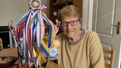 Edna Fletcher with a trophy and several medals 