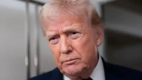 Donald Trump wearing dark suit looks off camera