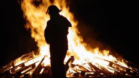 Silhouette of firefighter and bonfire