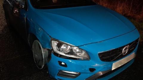 A blue Volvo with a wheel rim showing