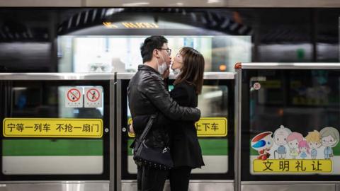 A couple kiss each other with their masks off while waiting for a train in Shanghai.