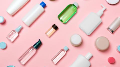 Rows of cosmetics and toiletries lined up against a pink background.