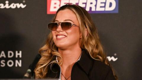 Francesca Hennessy grins at a news conference, wearing sunglasses