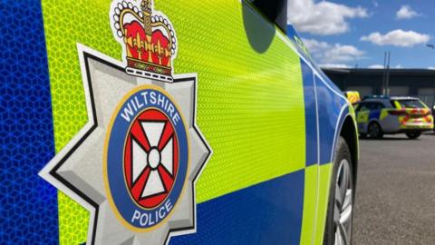 The side of a police car with the Wiltshire Police logo on it