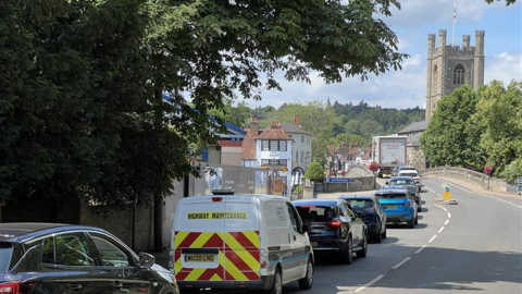 Cars and vans stuck on the left side of the road in Henley-on-Thames. The right side of the road is empty 