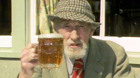Fyfe Robertson sits outside and holds up a pint

