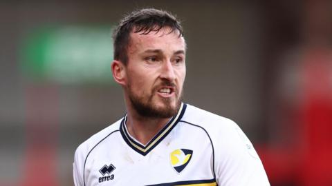 Luke Young on the pitch for Cheltenham, wearing their away kit, during a match this season
