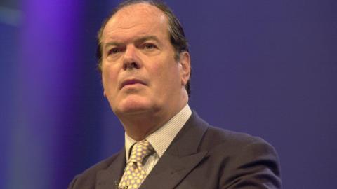 A head and shoulders photograph of former Lincolnshire MP Quentin Davies. He has receding dark hair and is wearing a grey suit with a yellow and purple tie.