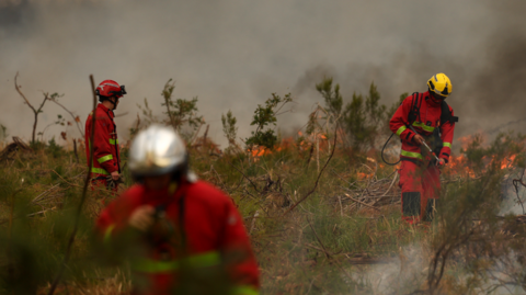 Firefighters of Paris Fire Brigade survey the scene amid the smoke and fire in Marcheprime west of Bordeaux on July 26, 2026 as a wildfire has been ravaging the forest north of the Arcachon Basin (Gironde) since July 22. The fire that has engulfed the area around the Arcachon Basin and is now threatening the outskirts of the Bordeaux metropolitan area has destroyed 42,000 hectares of "burned area," the Gironde prefecture announced; the prefecture has evacuated a total of 220,000 people since July 22. 