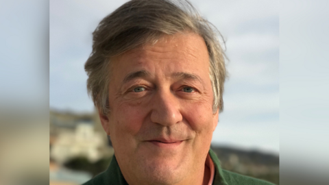 A portrait photo of Sir Stephen smiling at the camera