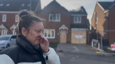 Diane Wilkinson standing in front of the house which has been damaged by fire.