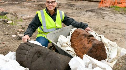 Volunteers with the Roman heads in two wheelbarrows