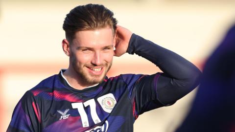 Crewe Alexandra's Joel Tabiner smiles and scratches the back of his head during a warm-up session