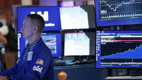 A stock market trader monitors screens on the stock market