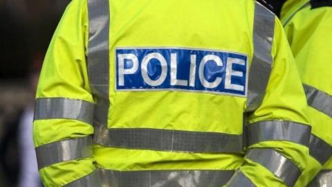 A stock image of a neon yellow police vest with the word police written on the back in white letters on blue background.
