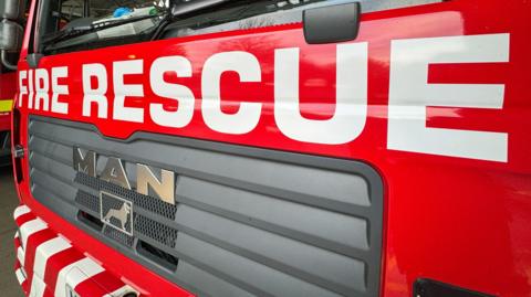 A close-up of the front of a fire engine with the words FIRE RESCUE in white text on the front.