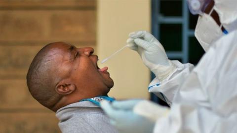 A man reacts before receiving a throat swab administered by a public health official wearing personal protective equipment (PPE) at a site for mass testing for the COVID-19 coronavirus in Ruaraka, a densely populated suburb in Nairobi on May 28