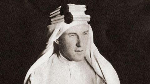 A black and white photo of Col T.E.Lawrence wearing a white Arab robe and headdress.