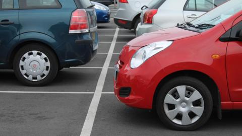 Two rows of vehicles parked in spaces at a car park.