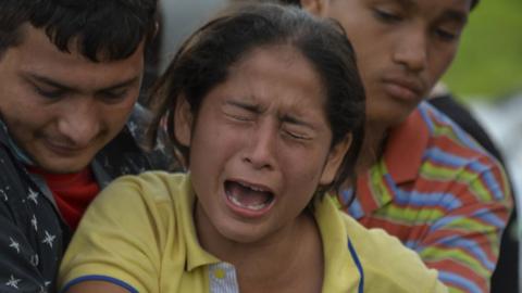 A woman mourns over the coffin of her father