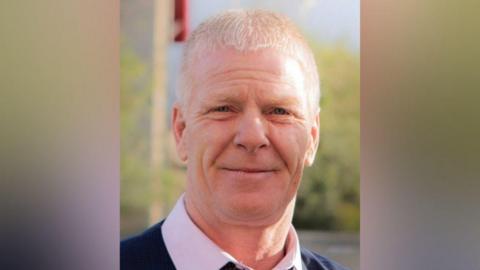 A Facebook picture of Colin Scott looking straight at the camera. He has short, white hair and is smiling