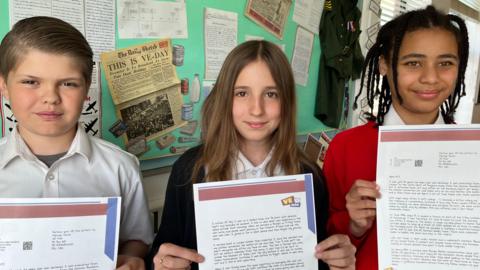 Schoolchildren hold up letters