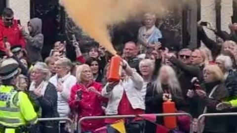 Woman sprays paint into air over crowd at Chester Cathedral