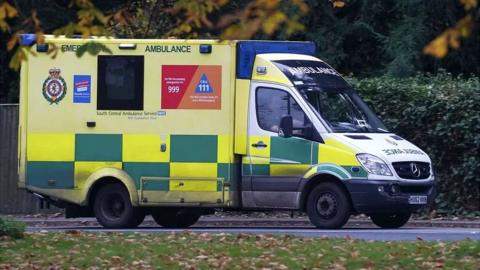 A South Central Ambulance Service branded ambulance on a road during autumn, with trees in the background