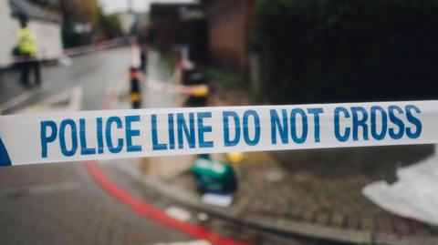 Police white and blue cordon tape separating the crime scene. - stock photo
