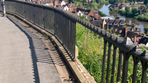 Railings beside a footpath with a section missing and behind them a view of the River Severn and Bridgnorth