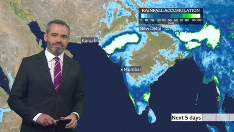 Forecaster Ben Rich stands in front of a weather map showing rainfall accumulation over the next 5 days in India