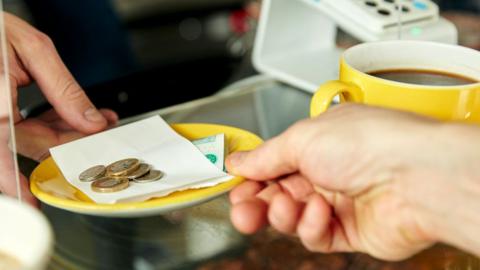 A person paying with cash in a cafe