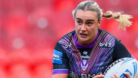 Paige Travis carries the ball for St Helens under her arm and her hair trails behind in a dinosaur plait