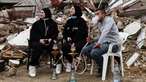 Returning residents sit at a damaged site, as Israeli troops withdrew from most of south Lebanon, in the southern Lebanese village of Kfar Kila, Lebanon,