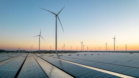 wind turbines and solar panels at dawn.