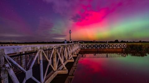 The Northern Lights in Tewkesbury over some water.