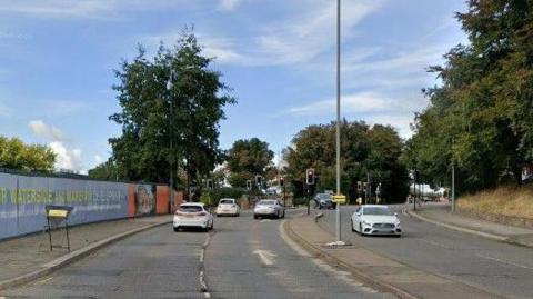 A dual carriageway road with cars driven in both directions and a narrow central reservation to keep lanes in different directions apart.
