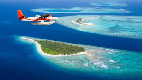 A plane flies above the Maldives