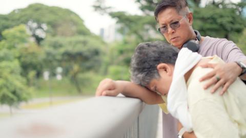 A woman leaning her head on railings with is being helped by a man