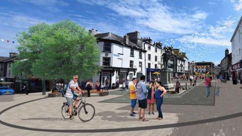 An artist's impression of how Kendal's Market place will look following the investment. The area is paved. In the foreground, a man rides a bike while four people nearby stand chatting. A war memorial can be seen behind them, as well as a row of shops and there are two large trees on the left of the image.