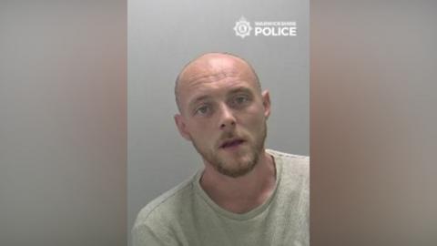 A police mugshot of a man wearing a t-shirt.
