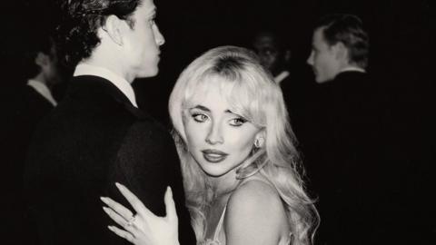 Black and white image of Sabrina Carpenter holding a man's arm