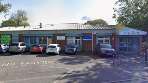A nursery building with a small car park in front of it.