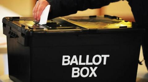 A black box with the words ballot box in white lettering on the side