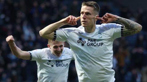 Preston striker Emil Riis places his fingers in his ears to celebrate 