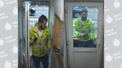 A man in a dirty high-visibility jacket walks through a white door. 