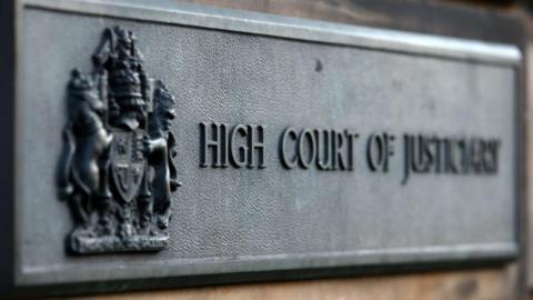 Grey 'High Court of Justiciary' sign in Edinburgh.